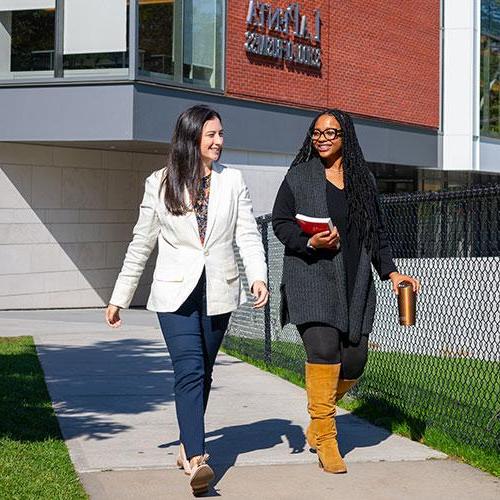 Two female students walking outside of LaPenta Business School